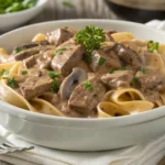 Healthy beef stroganoff with whole wheat noodles and fresh parsley in a white bowl.